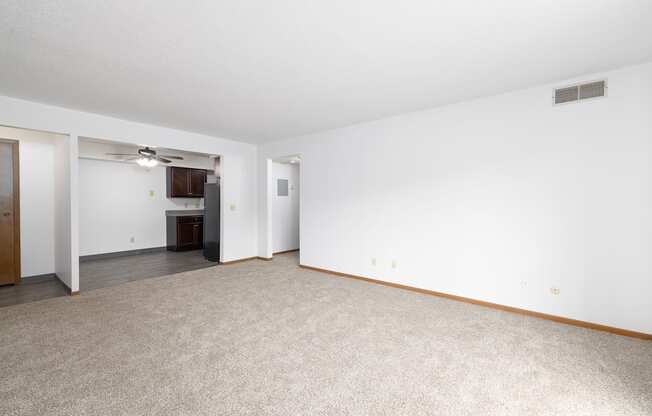 A spacious room with a carpeted floor and a ceiling fan.