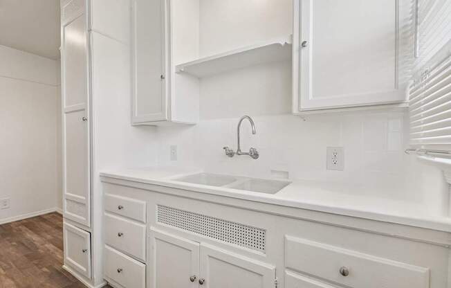A white kitchen with a sink and cabinets.