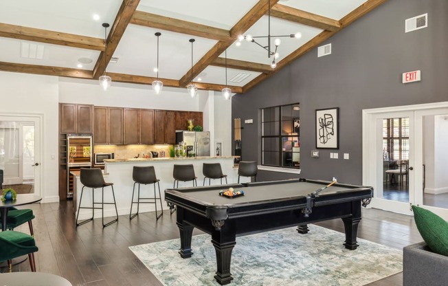 an open living room with a pool table and a kitchen with a bar