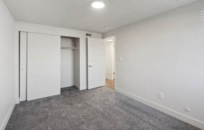 A room with white walls and a grey carpet.
