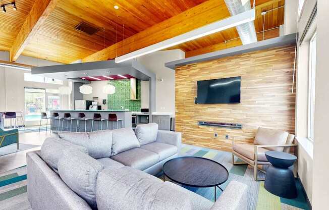 A modern living room with a grey sofa and a wooden wall.