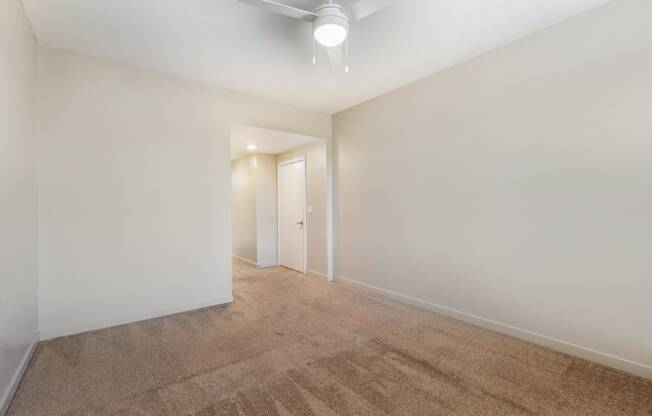 a living room with white walls and carpet and a ceiling fan at Metro Gateway, Riverside, 92503