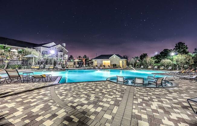 a large swimming pool at night with chairs around it  at Waterstone at Cinco Ranch, Katy, TX, 77450 