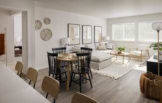 an open concept living room and dining room with white walls and hardwood floors