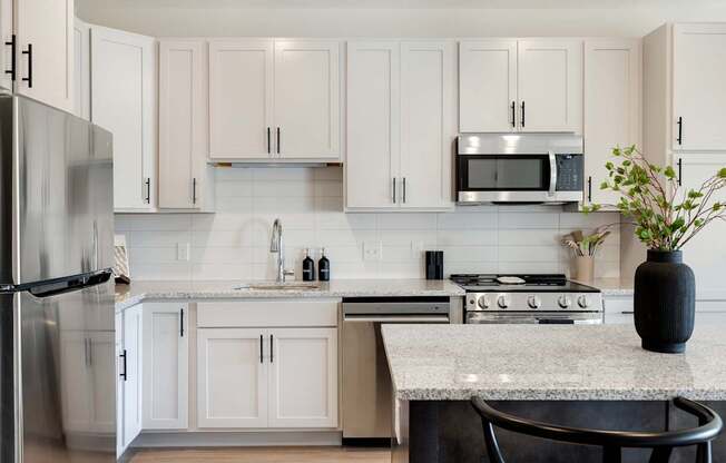 A kitchen with white cabinets and a granite countertop.