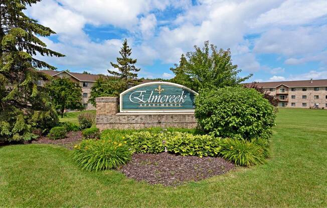 a sign for the entrance to an apartment complex with a building in the background