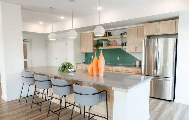 A modern kitchen with a long island and grey barstools.