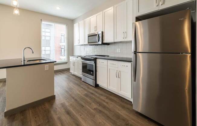 A modern kitchen with a stainless steel refrigerator and wooden floors.