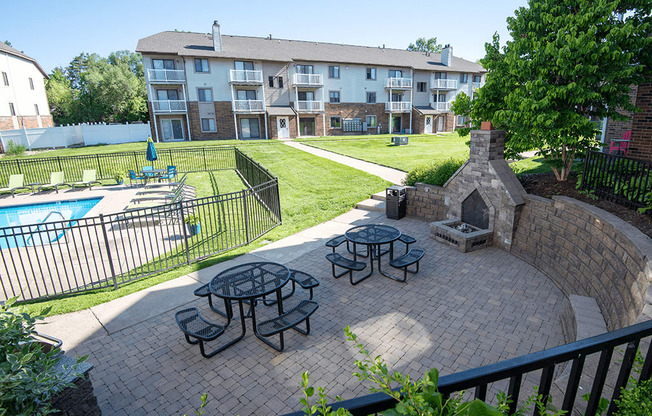 an outdoor patio with picnic tables and a pool in front of an apartment building