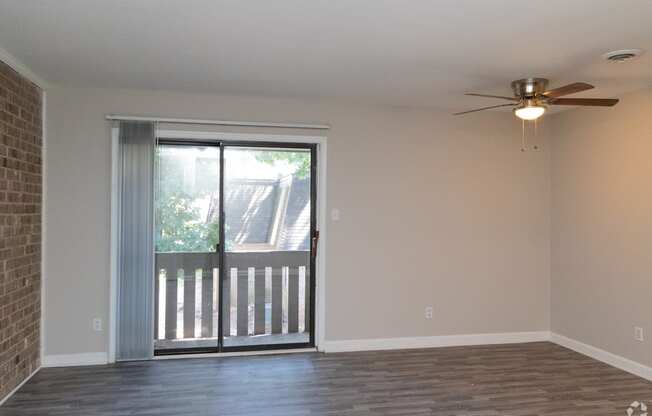 an empty living room with a sliding glass door and a ceiling fan