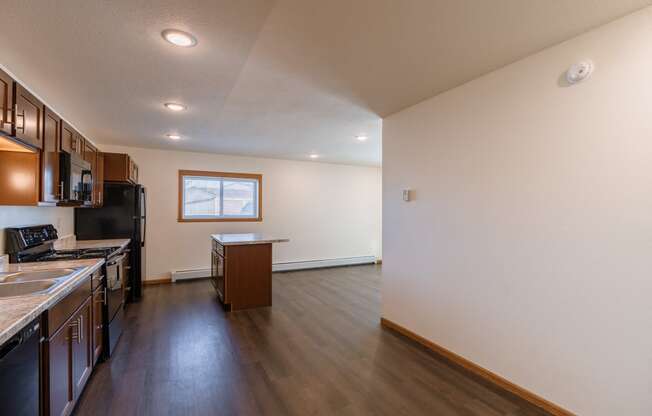 a kitchen with black appliances and a window with a dining room. Fargo, ND Westwood Apartments