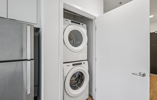 A white washing machine is in a white cabinet.