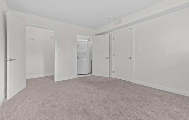 the living room of an apartment with white walls and carpet