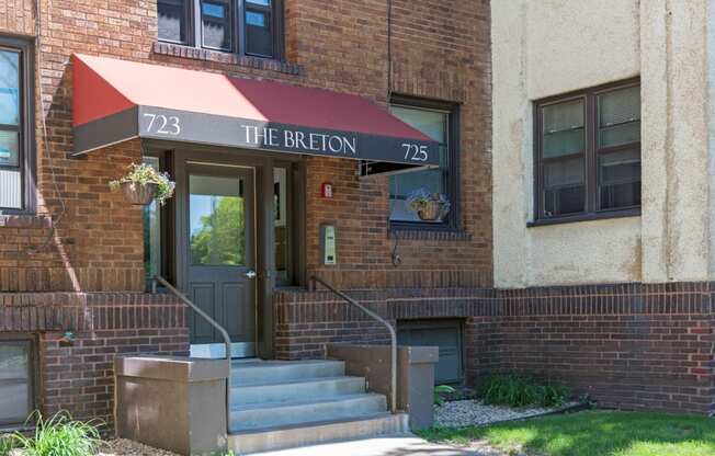 the front of a brick building with stairs and a red awning