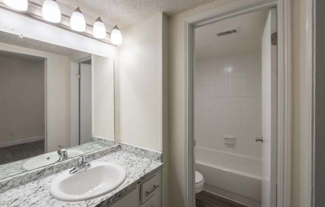 A bathroom with white vanity 1 bedroom, 1 bath apartment home at Princeton Court Apartments in the Vickery Midtown neighborhood of Dallas, TX.