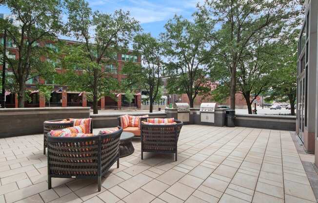 a patio with chairs and a table and trees