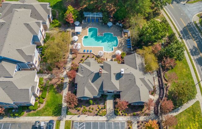 An aerial view of a residential area with houses, a swimming pool, and a parking lot.