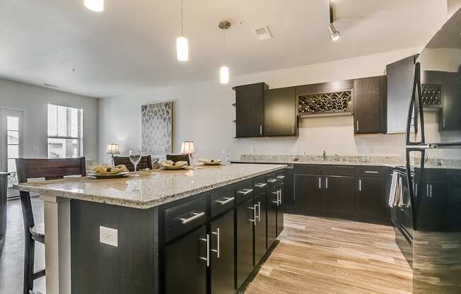 a kitchen with dark cabinets and a large island with granite countertops