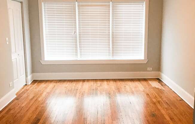 an empty living room with wood floors and a ceiling fan