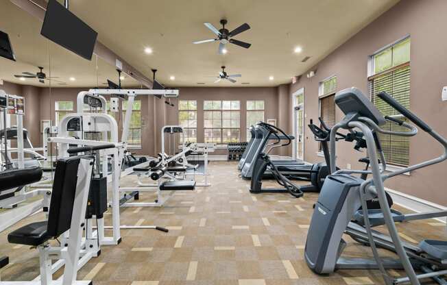 a gym with weights and cardio equipment and a ceiling fan