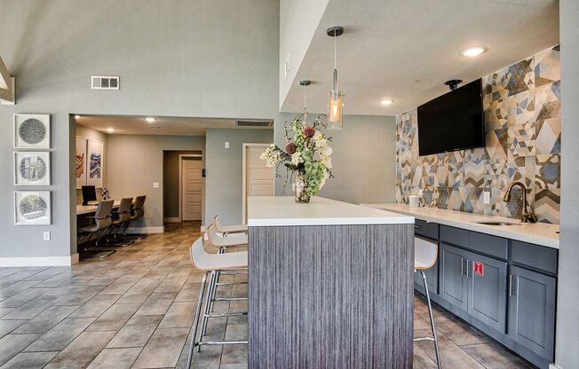 A modern kitchen with a bar area and a television mounted on the wall.