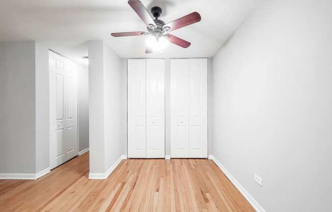 a bedroom with two closets and a ceiling fan