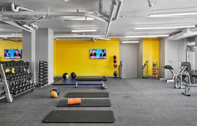 A gym with a variety of equipment including weights, a bench press, and a treadmill.