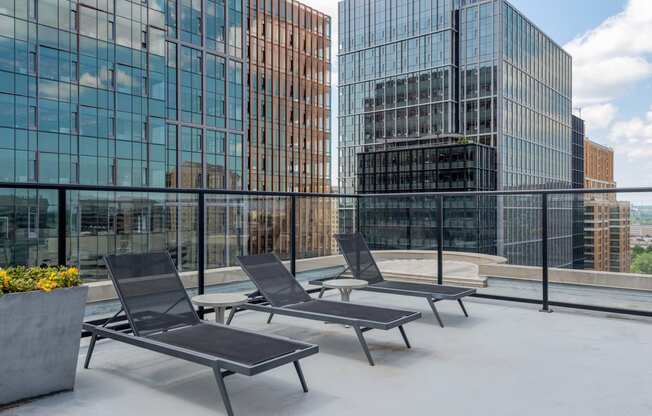 a group of lounge chairs on a rooftop terrace with tall buildings