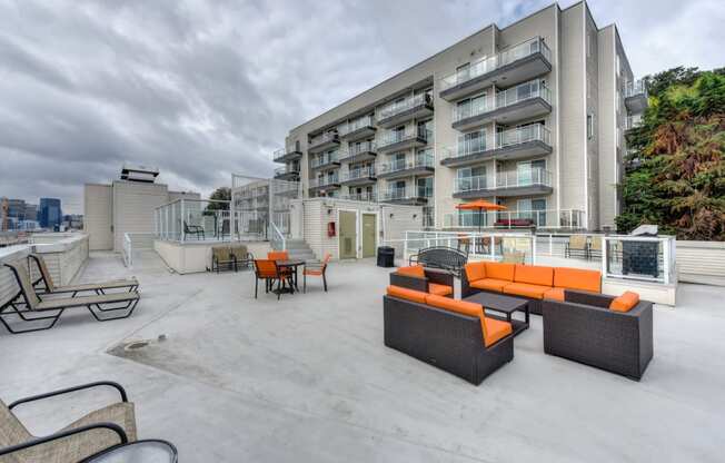 Rooftop Lounge Area with Orange Sofa, Lounge Chairs and Apartment Exterior