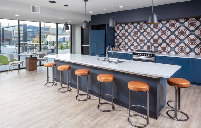a communal kitchen with bar stools and a large window with a city view at Maven on Broadway, Minnesota, 55904