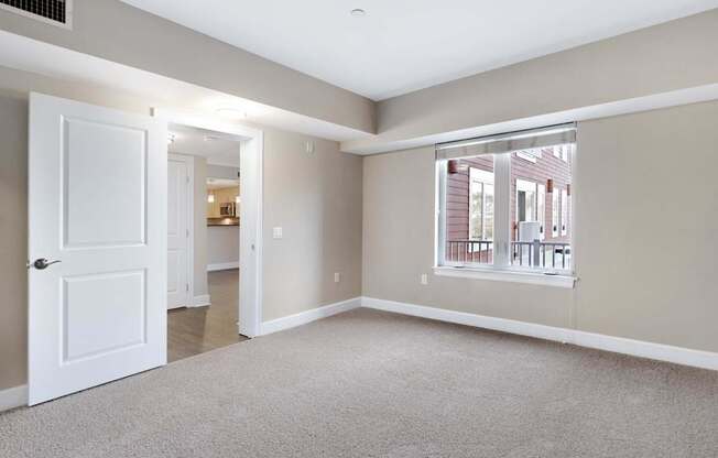A room with a white door and a window with a view of a building outside.