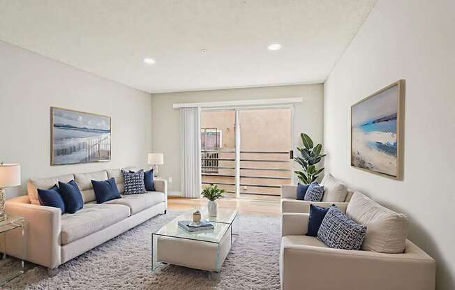A living room with a white couch, a glass coffee table, and a painting on the wall.