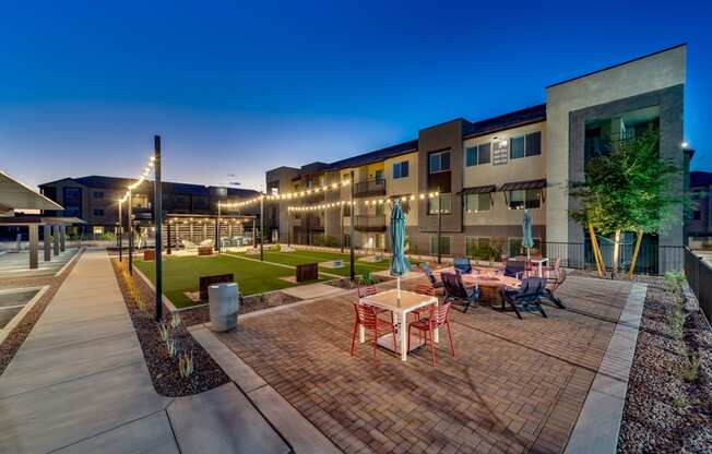 an outdoor patio with tables and chairs at night