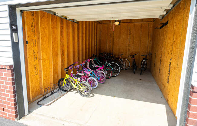 A garage with a wooden door is full of bicycles.