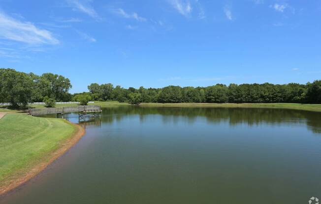 A serene lake surrounded by lush greenery under a clear blue sky.