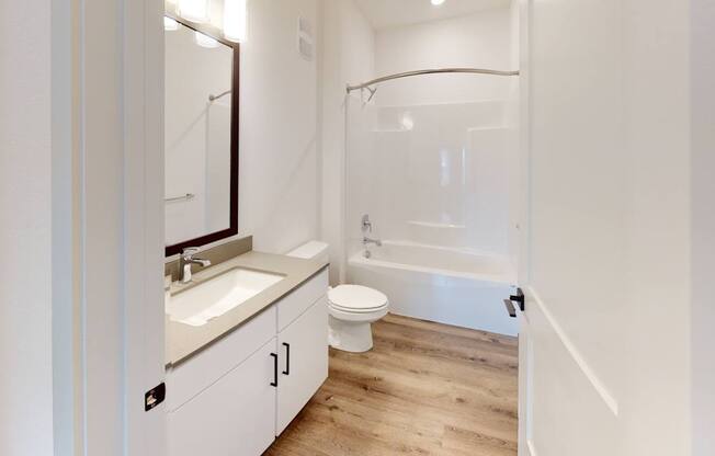 A white bathroom with a sink, toilet, and bathtub.