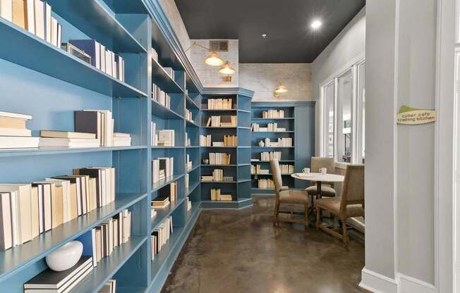 A room with blue bookshelves filled with books and a table with chairs at Prairie Crossing, Farmers Branch, TX