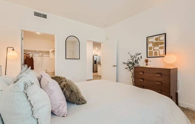 a bedroom with a large bed and a dresser with a mirror