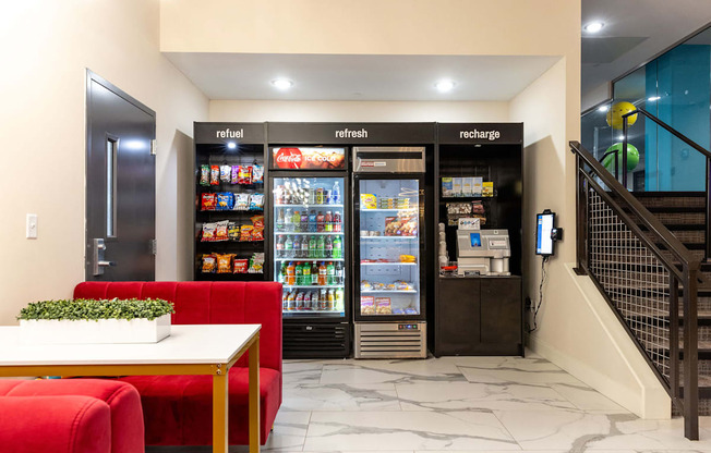 a lobby area with red couches and refrigerators    and a staircase