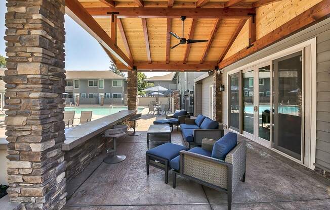 a covered patio with furniture and a pool in the background