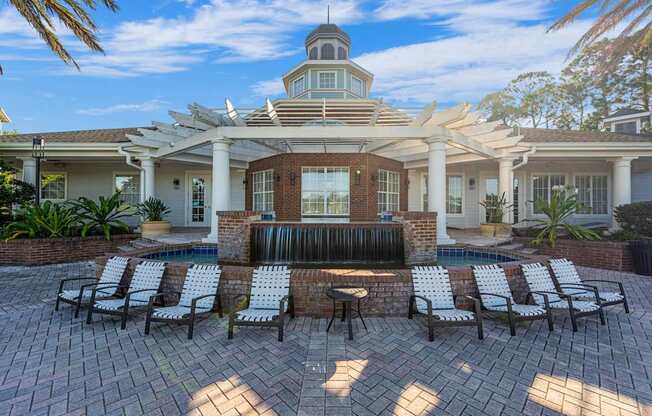 a patio with chairs and a fountain in front of a house
