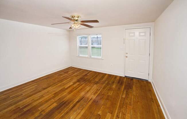 A room with a ceiling fan and wooden flooring.