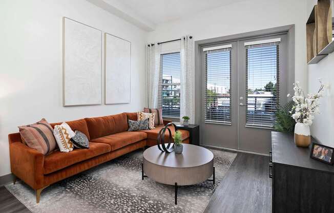 A living room with a brown couch, a round table, and a rug.