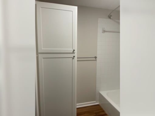 a bathroom with white cabinets and a shower and a sink