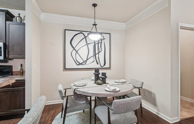 A dining room with a table set for two and a modern art piece on the wall.