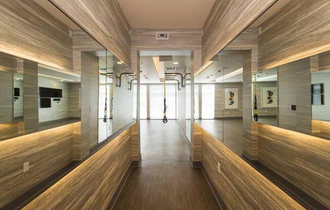 a view down the hallway of the fitness center with wooden benches and mirrors on the walls