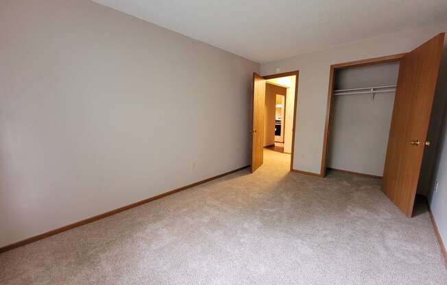 an empty bedroom with a closet and a door to a bathroom