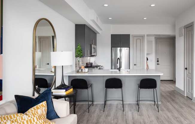 A modern kitchen with a white countertop and black bar stools.