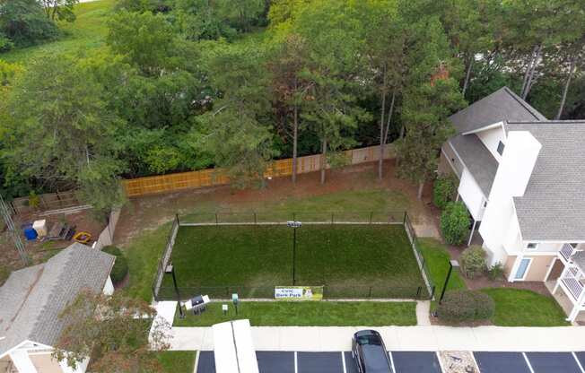 an aerial view of a yard with a tennis court and a house in the background