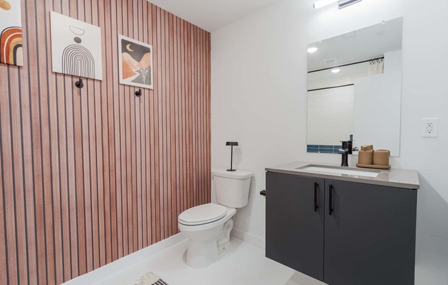 A bathroom with a toilet, sink, and striped wallpaper.